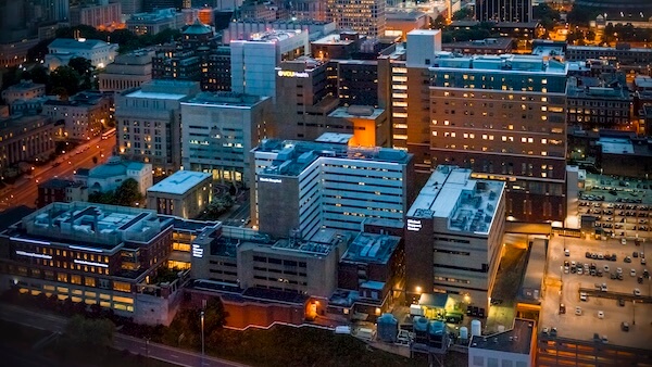 An aerial nighttime view of VCU Health’s sprawling hospital campus, with the Richmond cityscape in the background.